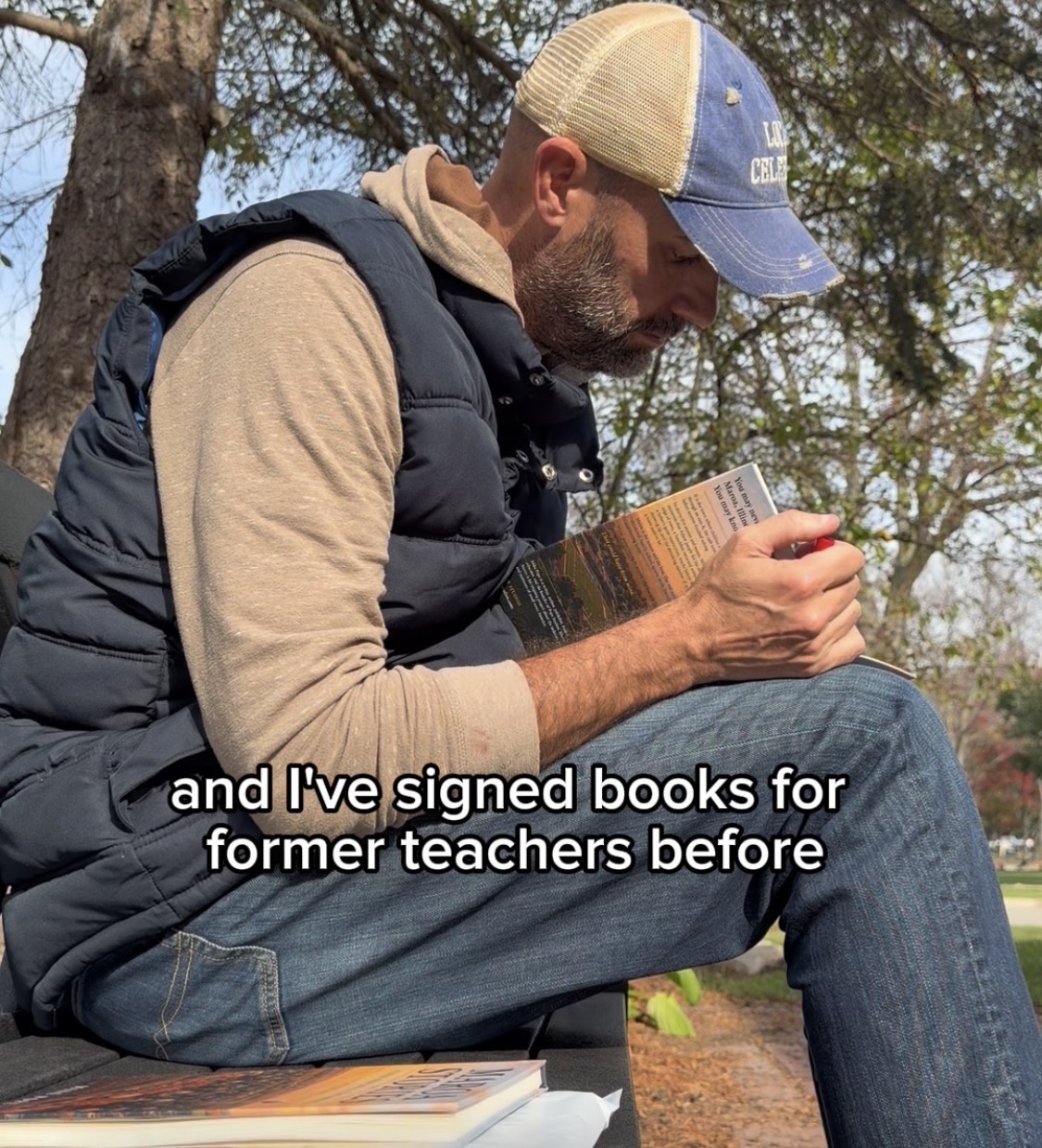 Mike Pope seated outdoors signing a book