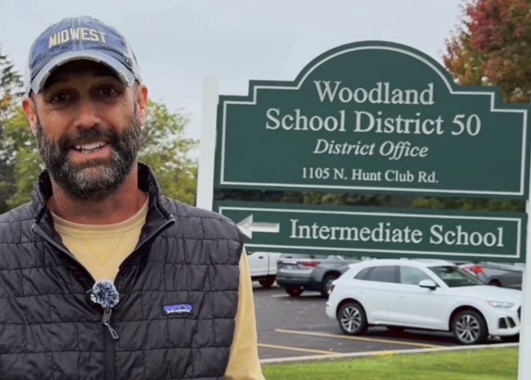 Mike Pope beside the Woodland School District 50 district-office sign in Gurnee